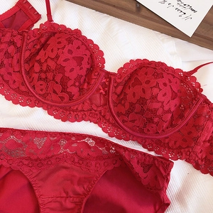 Detail shot of red floral lace bra and satin panties set on white striped background