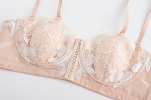 Close-up of beige French lace bra with intricate white rose embroidery and mesh detail