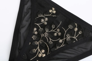 Detailed macro view of elegant floral embroidery on breathable black mesh fabric