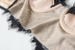 Vista dettagliata del tessuto a rete beige e del pizzo nero sulle coppe del reggiseno con ferretto