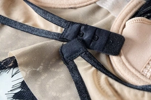 Dettaglio della chiusura posteriore a tre file di ganci sul reggiseno beige in pizzo