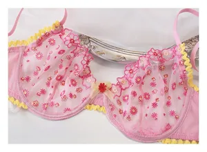 Dettaglio di reggiseno in pizzo rosa con ricamo di margherite e bordi a conchiglia
