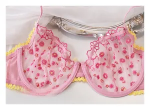 Dettagli del ricamo su reggiseno in rete rosa con finiture gialle e supporto con ferretto