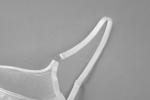 Detail view of white mesh lingerie with thin straps and silver metal ring connectors