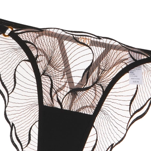 Detailed close-up of sheer black lace panties with leaf embroidery and metal ring