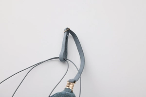 Detail of adjustable metal gold buckle and gray blue shoulder strap texture on a bra