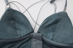Close-up of dark blue denim bralette with thin straps and intricate cross-back lacing