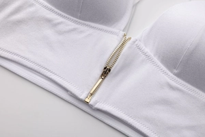 Close-up of white knitted fabric with gold zipper and square pendant detail