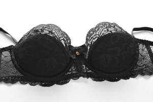 Détail d'un soutien-gorge en dentelle noire avec motifs floraux et anneau doré