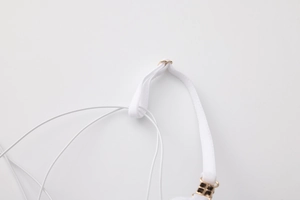 Detail of white thin shoulder strap with a gold heart-shaped metal adjustment buckle