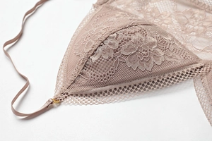 Detail of floral lace mesh bra featuring scalloped edges and gold metal strap hardware