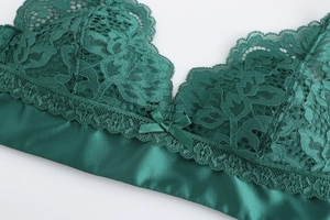 Detail of dark green French lace bra featuring floral textures and a satin bow finish