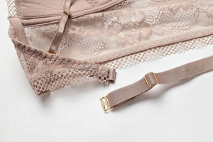 Detailed view of dusty pink lace bra featuring floral patterns and gold metal adjusters