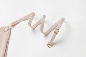 Detail of adjustable elastic straps with gold metal hooks on a nude lace bralette