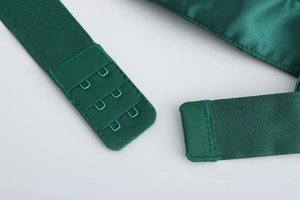 Detail of dark green lace bra showing two-row hook and eye back closure and satin fabric