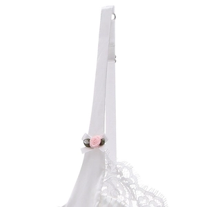 Detail of white satin lingerie featuring delicate lace edges and pink rose ribbon bow
