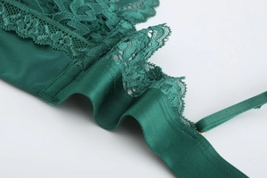 Detail of dark green lace lingerie featuring adjustable thin shoulder straps and satin fabric