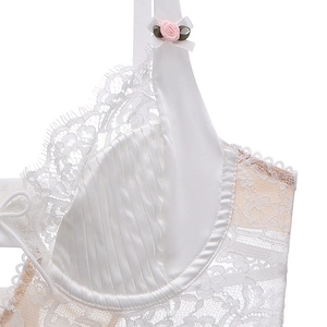 Close-up of white satin pleats and delicate eyelash lace with small floral detail