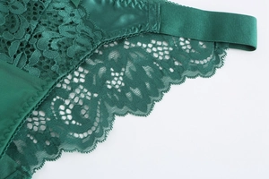 Close-up of elegant dark green lace floral embroidery and silky satin lingerie fabric