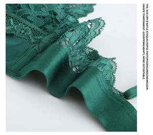 Detail of dark green lace bra showing intricate floral embroidery and silky fabric texture