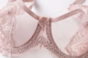 Detailed macro view of pale pink floral lace and breathable mesh on a thin balconette bra