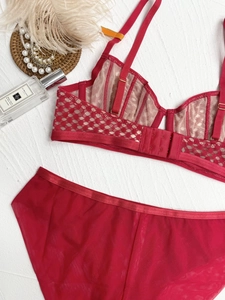 Flat lay of red lace lingerie set with mesh details on white textured background