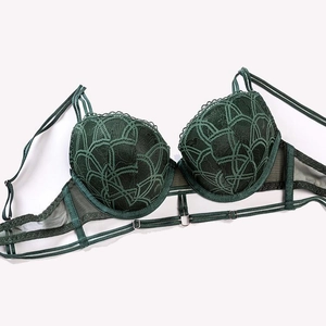 Close-up of deep green lace bra featuring intricate wavy patterns and mesh side wings