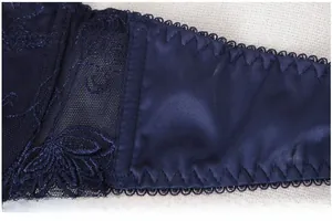 Detailed macro view of navy blue lace embroidery and elastic satin side wing of the bra