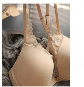 Detailed close-up of beige front-closure lace bra with floral straps on plush fabric