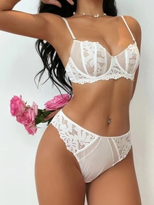 Detailed view of white floral lace embroidery and sheer mesh texture on luxury bra set