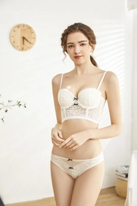 Detail of white floral lace lingerie set featuring black bow accents and delicate patterns