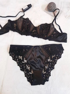 Detailed flat lay of black lace and satin lingerie set with embroidered mesh texture