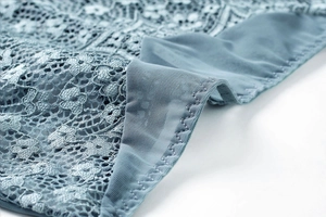 Detailed close-up of light blue lace and mesh fabric with delicate floral embroidery