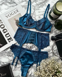 Three-piece lace lingerie set with garter belt on marble background with luxury props