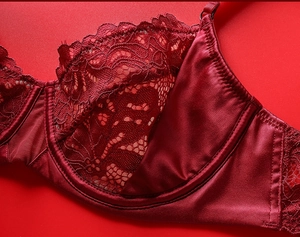 Detailed macro view of dark red floral lace embroidery and satin silk bra texture