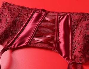 Detail of red lace lingerie featuring corset lacing and satin floral patterns