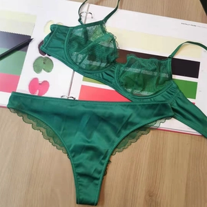 Deep green lace lingerie set with sheer mesh bra and matching panties on wood