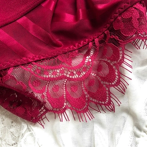 Detailed macro view of dark red satin fabric with delicate eyelash lace and mesh material