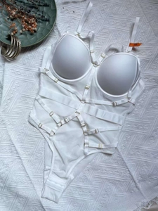 Détail d'un body blanc avec anneaux dorés réglables et conception à sangles croisées