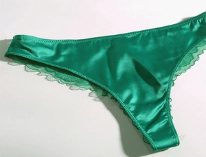 Close-up of emerald green satin underwear with delicate lace trim for a luxury feel