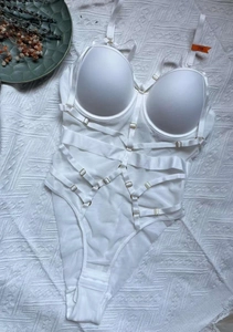 Détails à plat d'un body blanc à lacets avec doubles bretelles et boucles dorées