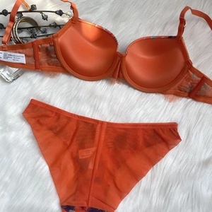 Detailed view of the bright orange lace trim and semi-transparent mesh underwear set