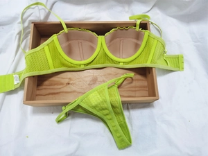 Detailed flat lay of fluorescent green lace bra and thong set on a wooden tray