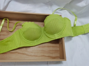Detailed close-up of fluorescent green lace mesh bra with underwire on wooden tray