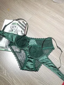Ensemble lingerie en dentelle vert foncé à motif léopard posé sur un sol en bois
