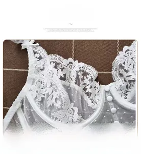 Détail de la dentelle blanche avec broderies et petits boutons sur un soutien-gorge