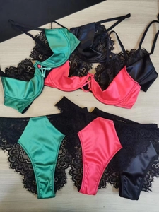 Three-color set of lace and satin lingerie in green, rose red, and black on wood