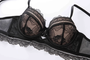 Detail of black floral lace overlay on nude cups with silver tassel pendant charm