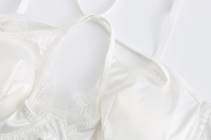 Détail de lingerie en satin blanc avec bordure en dentelle cils et design licou croisé