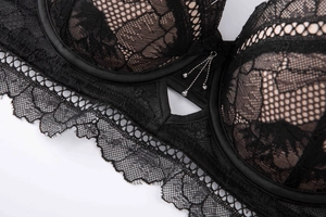 Macro detail of sexy black floral lace bra with elegant silver bead pendant